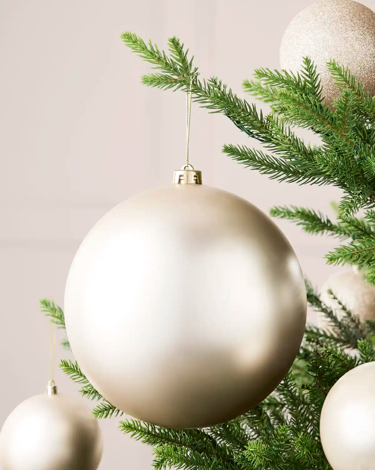 Latte 20 cm oversized matt shatterproof bauble displayed on a Christmas tree with coordinating latte baubles.
