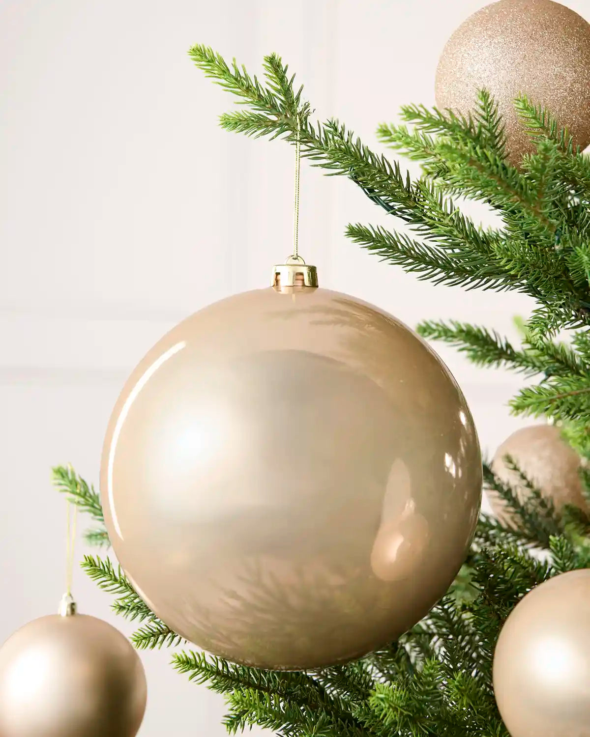 Latte 20 cm oversized shiny shatterproof bauble displayed on a Christmas tree with coordinating latte baubles.
