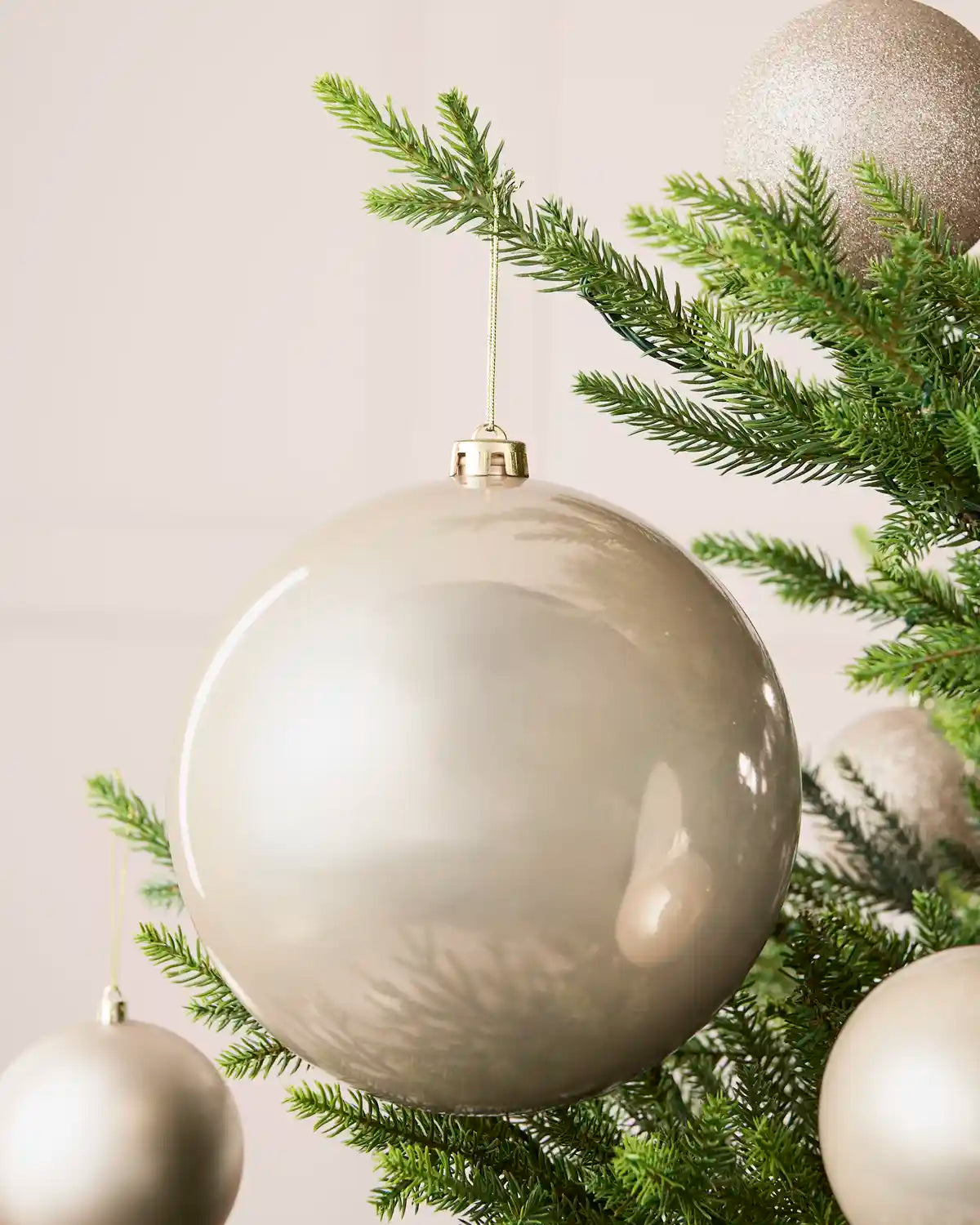 Latte 20 cm oversized shiny shatterproof bauble displayed on a Christmas tree with coordinating latte baubles.
