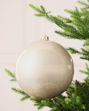 Latte 20 cm oversized shiny shatterproof bauble hanging on a Christmas tree with a gold cap and matching string.

