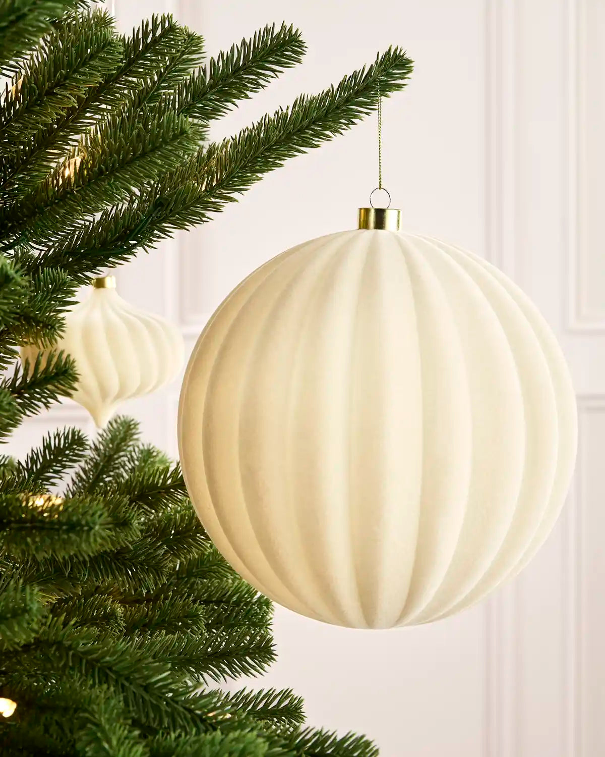 Latte 20 cm oversized velvet Ribbed bauble displayed on a Christmas tree with coordinating ornaments.
