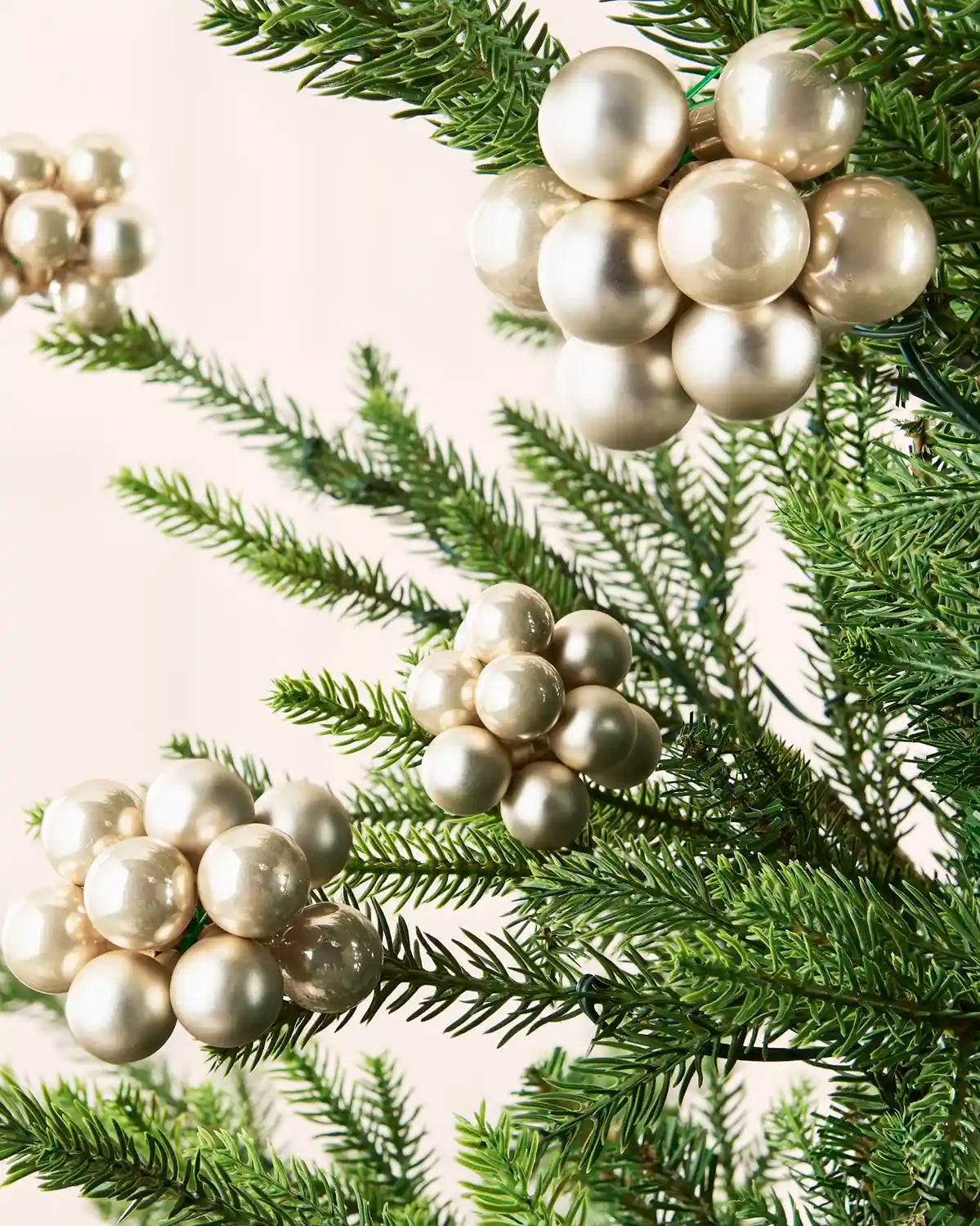 Latte berry cluster baubles with mixed shiny and matt glass finishes displayed on Christmas branches.
