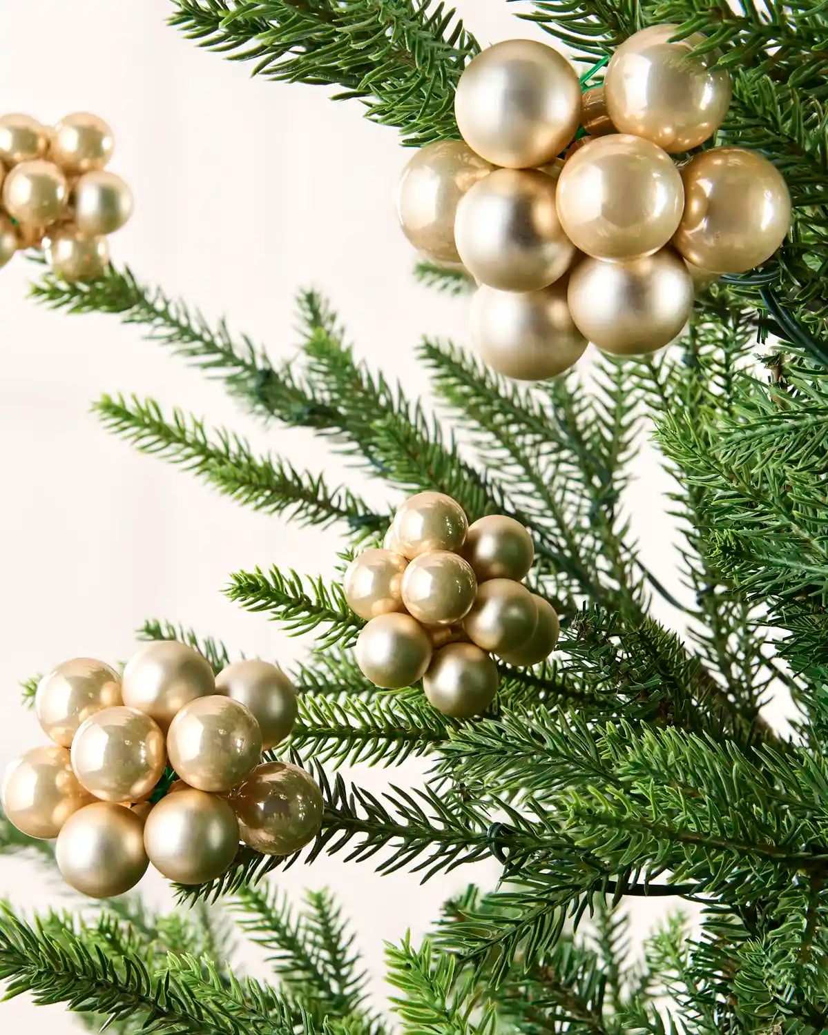 Latte berry cluster baubles with mixed shiny and matt glass finishes displayed on Christmas branches.
