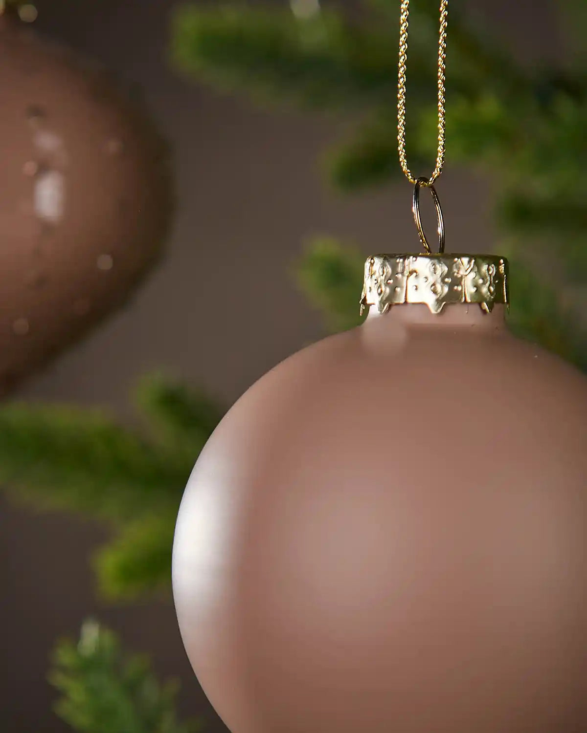 Latte coloured Christmas baubles with gold cap hanging on a tree