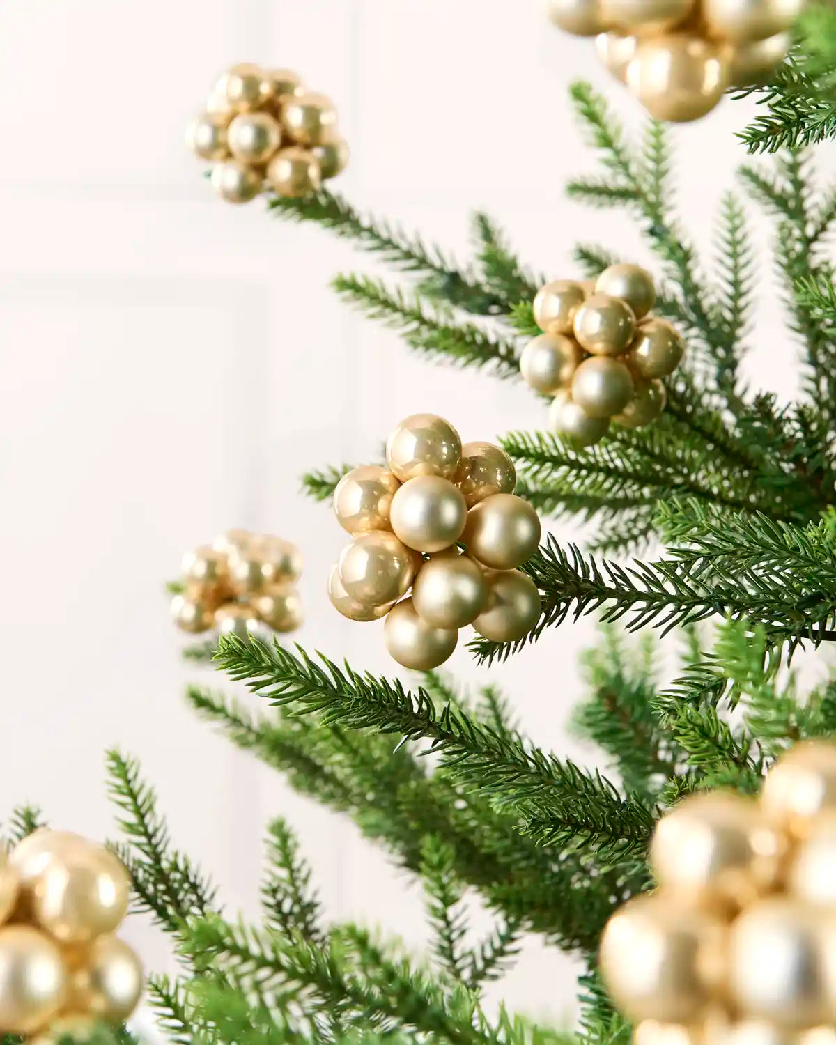 Latte glass berry cluster baubles arranged throughout a green Christmas tree.
