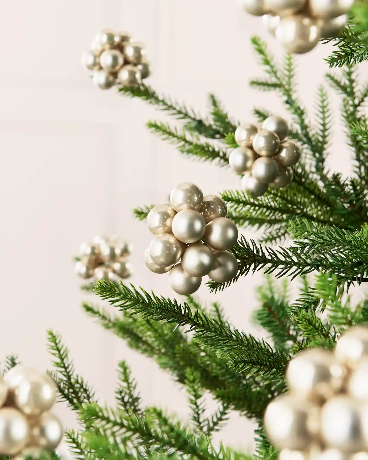Latte glass berry cluster baubles arranged throughout a green Christmas tree.

