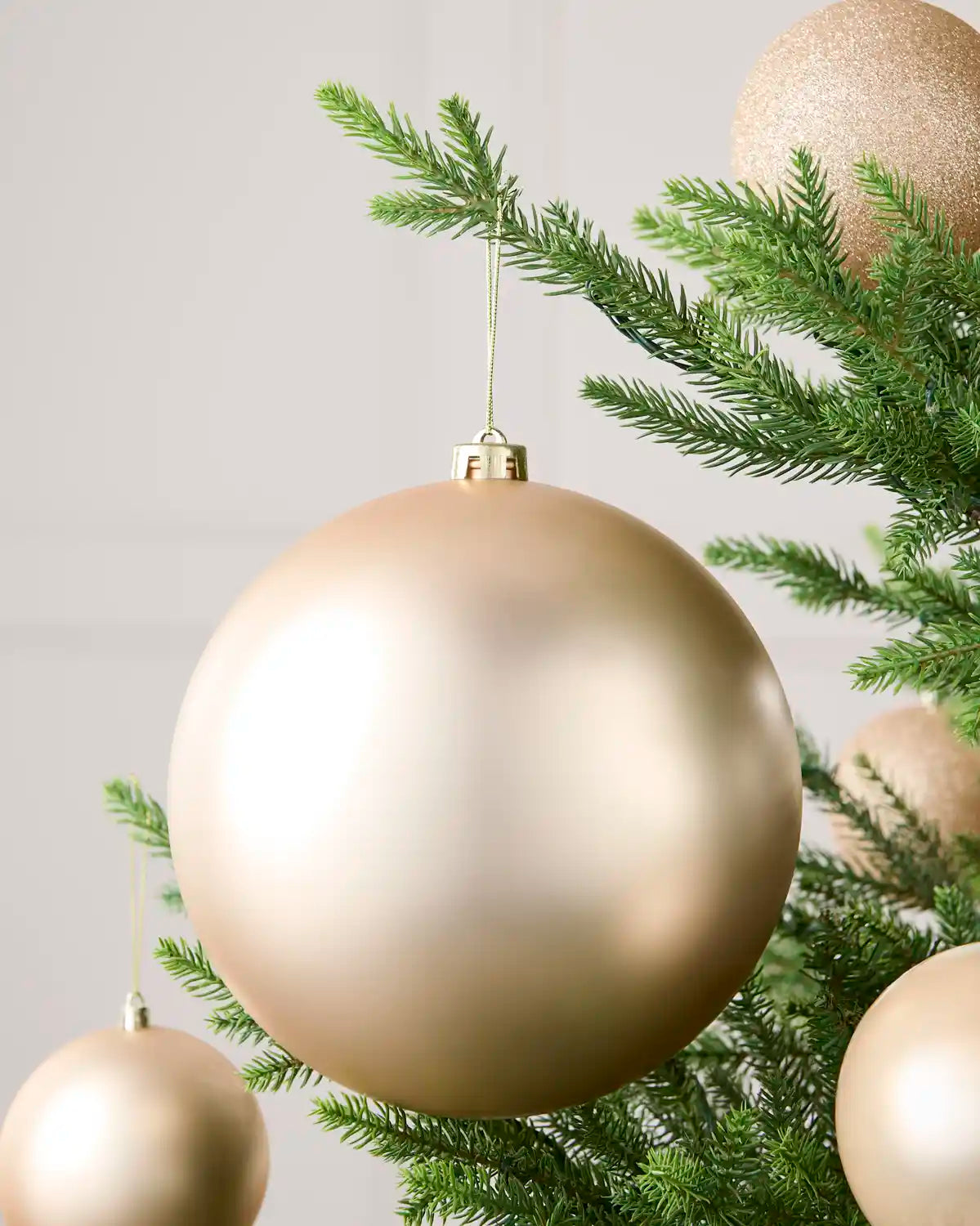 Latte 20 cm oversized matt shatterproof bauble displayed on a Christmas tree with coordinating latte baubles.
