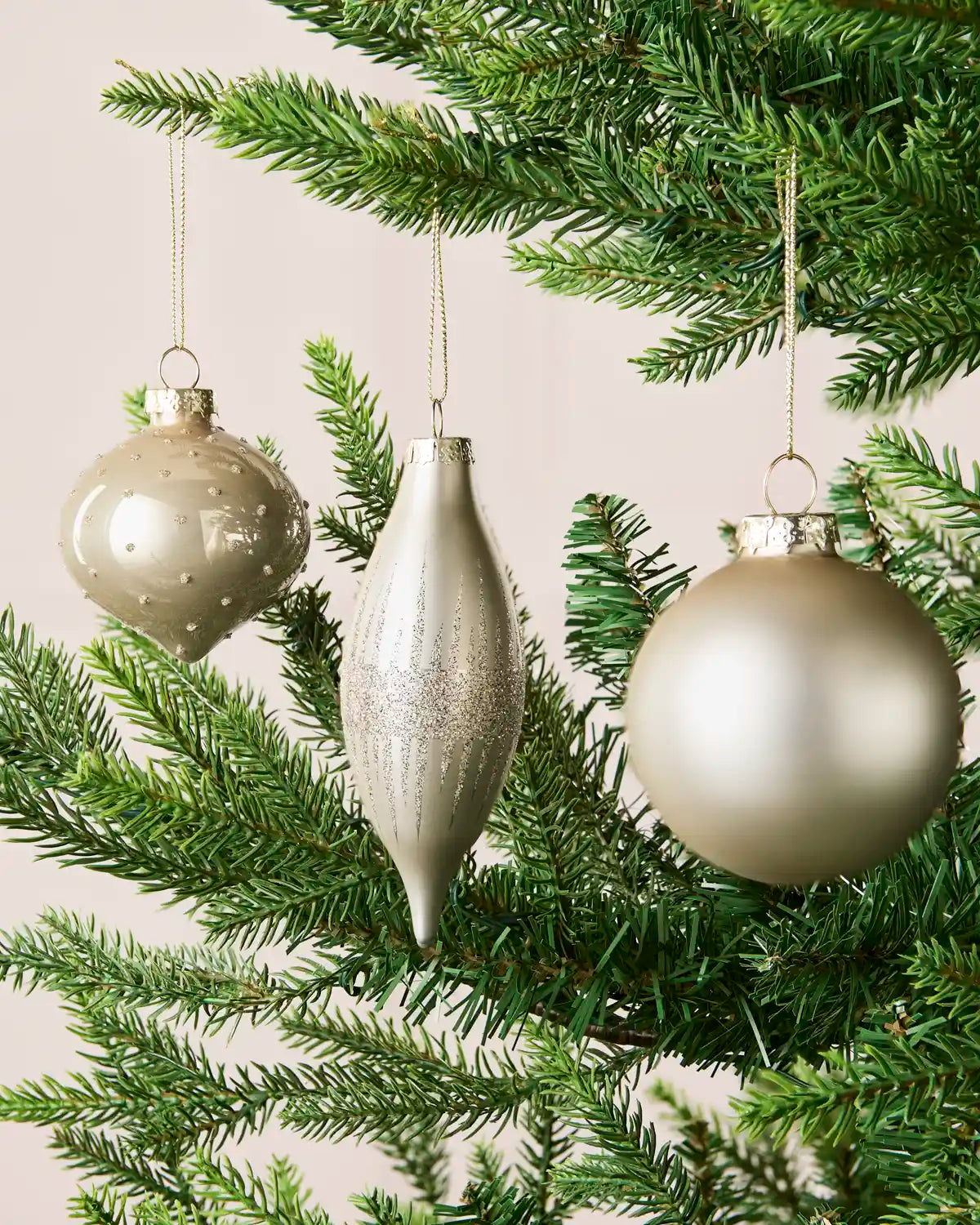 Latte round, onion-shaped and teardrop glass baubles displayed on a Christmas tree.
