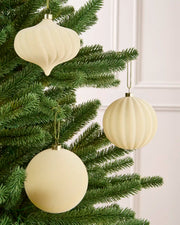 Latte velvet baubles classic round and onion shapes with smooth and swirl patterns, hanging from Christmas tree branches
