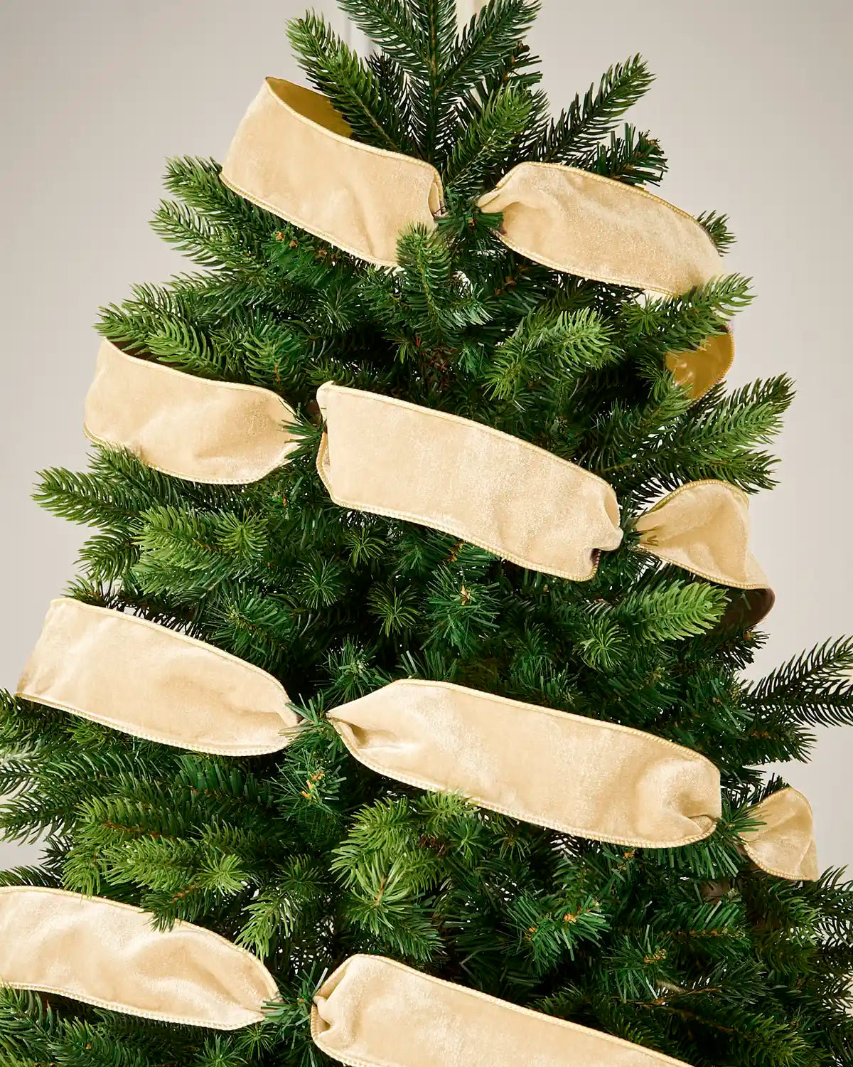 Latte wired velvet ribbon arranged around a Christmas tree for a soft neutral decorative finish.