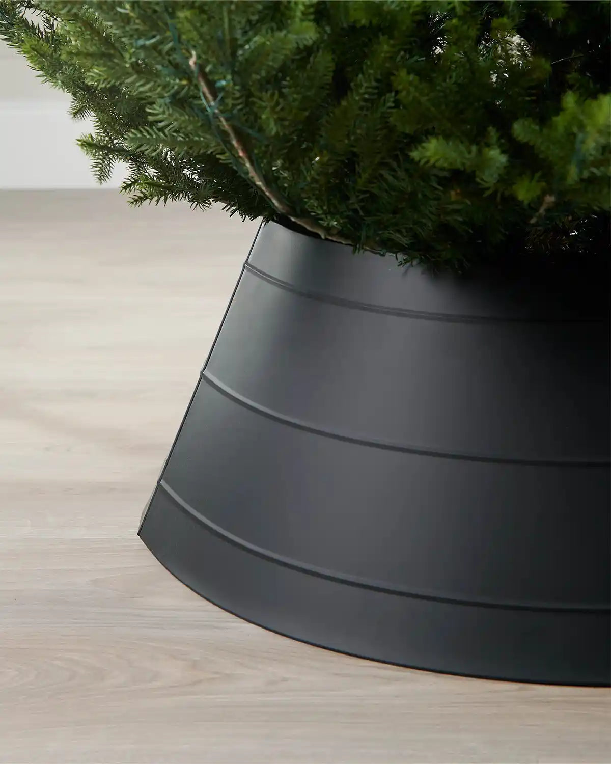 Close-up of left side of black metal tree collar on light wood flooring