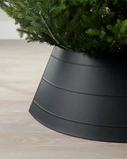 Close-up of left side of black metal tree collar on light wood flooring