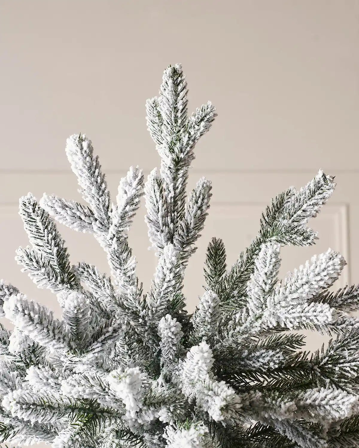 Close up of the top pf the tree showing PVC and PE snow flocked tips at the on the Luxury Snow Flocked Christmas Tree, 7ft on a Panel textured background