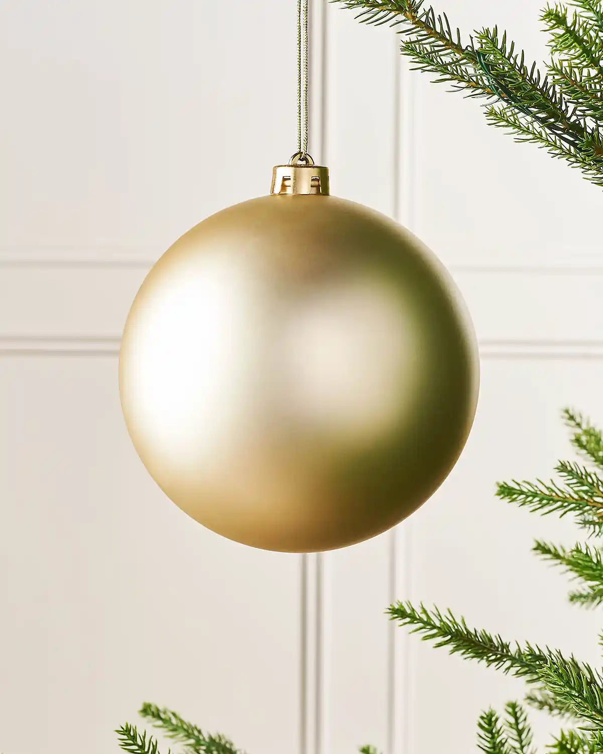 Matt gold 15cm oversized bauble on a Christmas tree branch