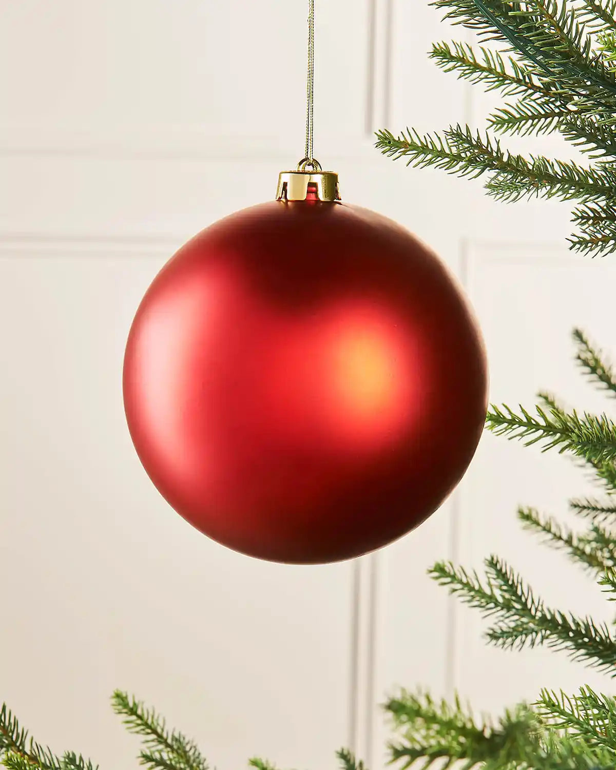 Matt red 15cm oversized bauble on a Christmas tree branch