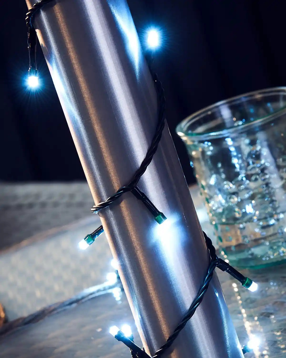 Metallic Umbrella pole with ice white string lights on a light grey wicker surface