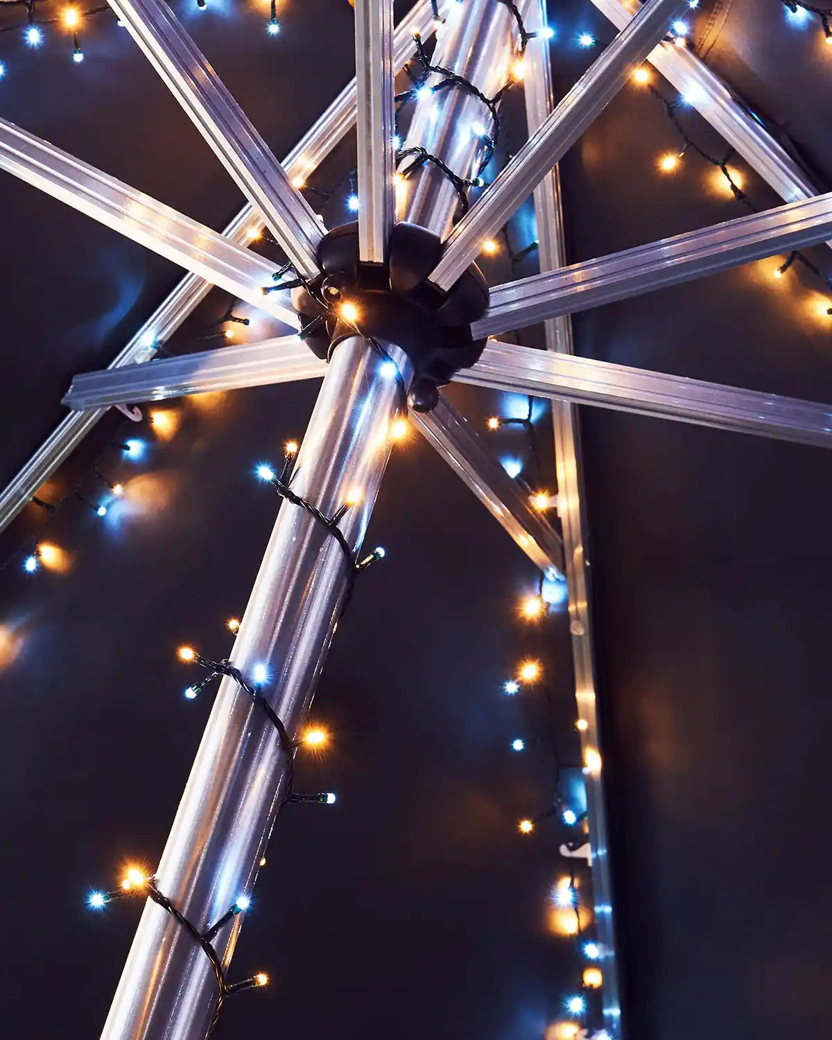 Metallic structure with warm white and ice white string lights against a dark background