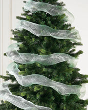 Mint green mesh fabric ribbon wrapped around Christmas tree against a cream panel wall