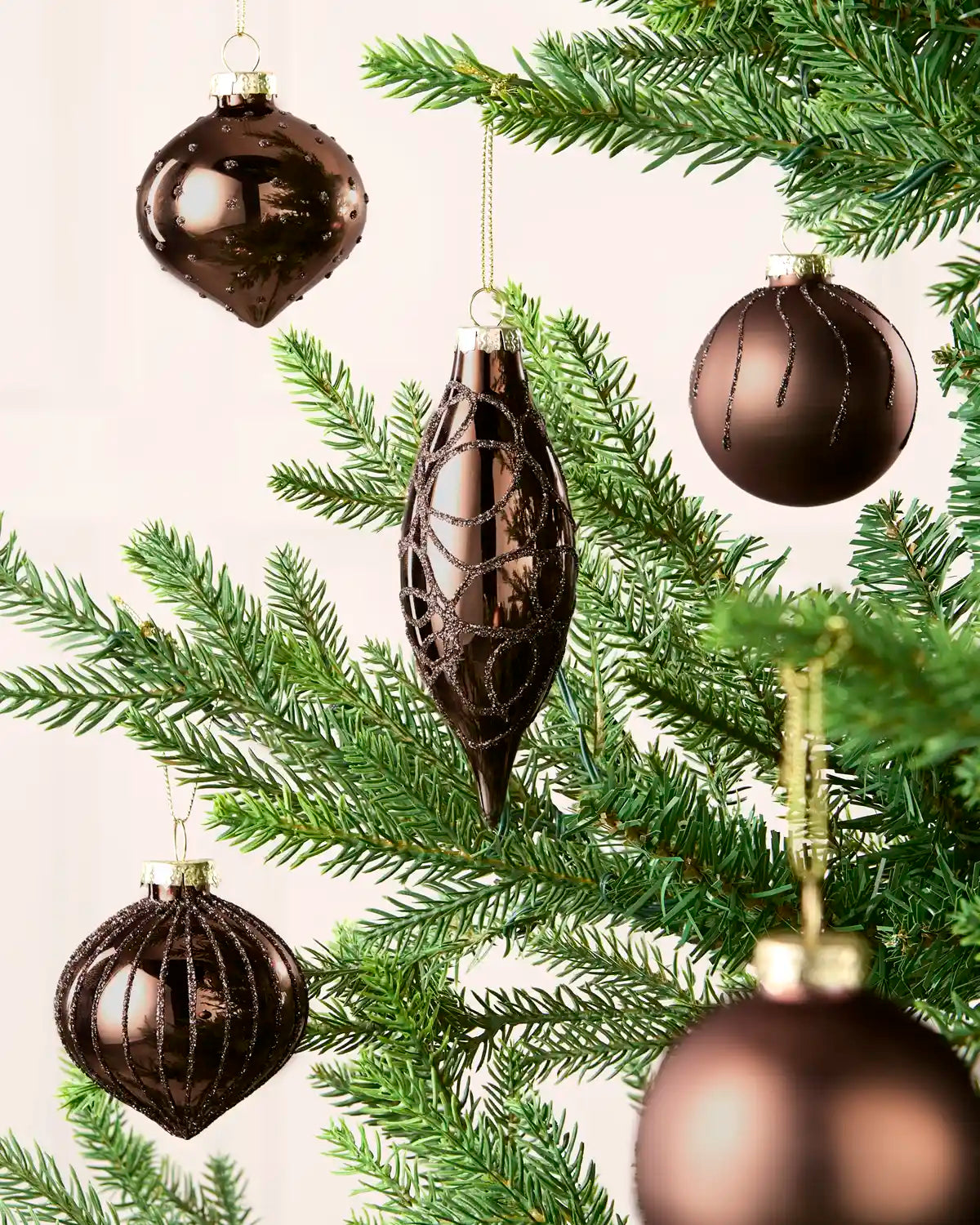 Mixed Espresso glass baubles with matt, shiny and glitter finishes on a Christmas tree.
