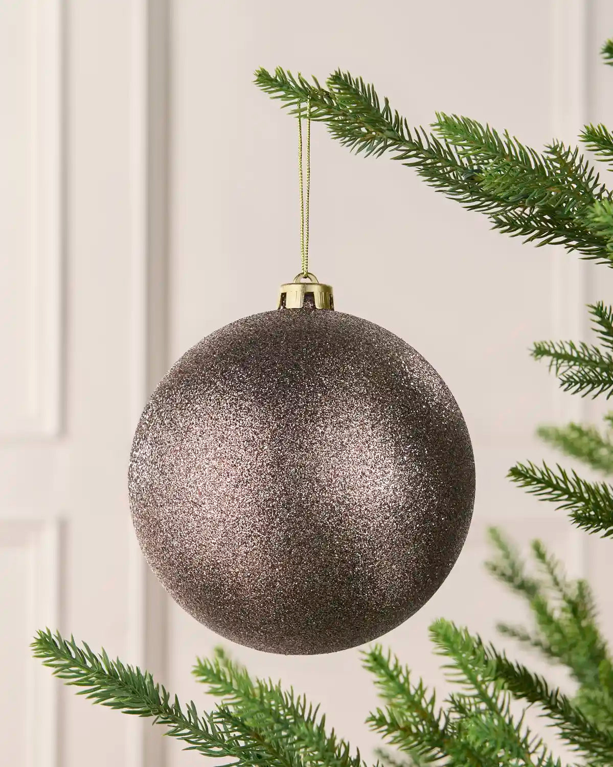 Mocha 15 cm oversized Glitter shatterproof bauble hanging on a Christmas tree with a gold cap and matching string.

