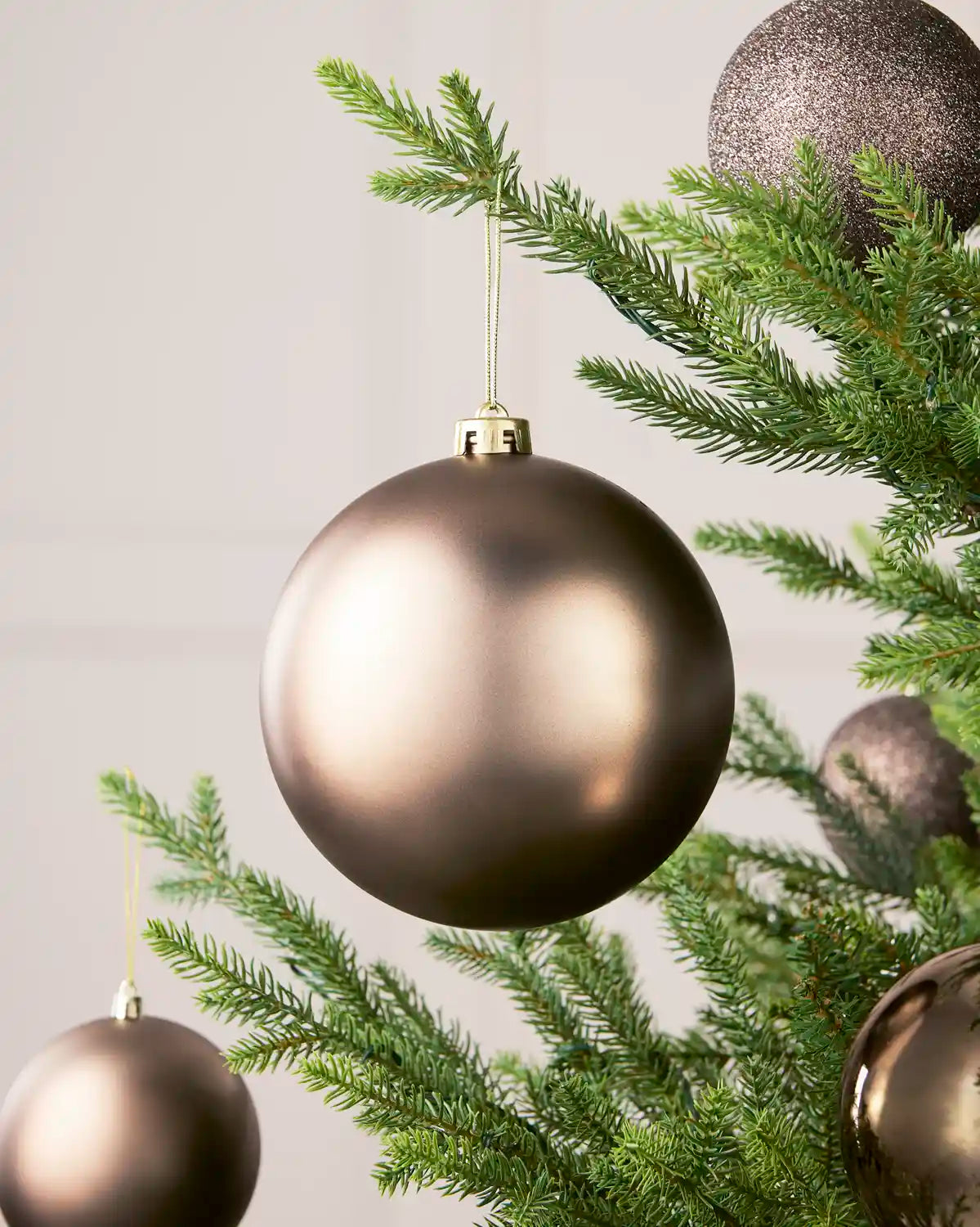 Mocha 15 cm oversized Matt shatterproof bauble displayed on a Christmas tree with coordinating Mocha baubles.
