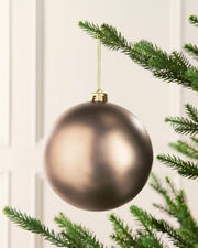 Mocha 15 cm oversized Matt shatterproof bauble hanging on a Christmas tree with a gold cap and matching string.
