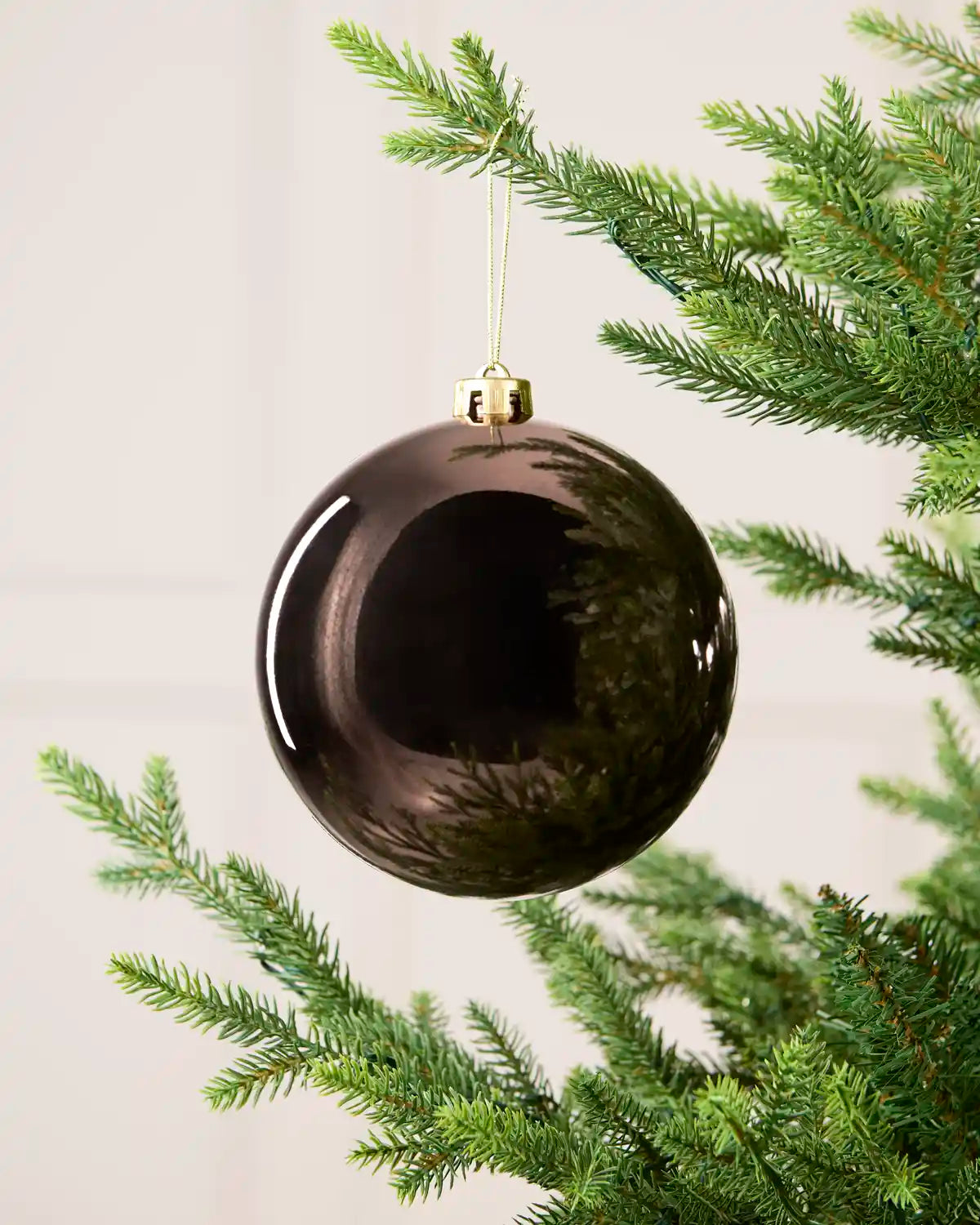 Mocha 15 cm oversized Shiny shatterproof bauble hanging on a Christmas tree with a gold cap and matching string.
