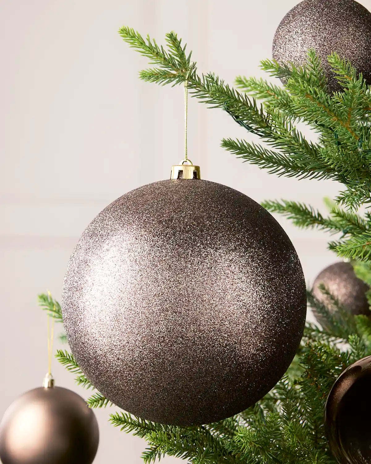 Mocha 20 cm oversized Glitter shatterproof bauble displayed on a Christmas tree with coordinating Mocha baubles.
