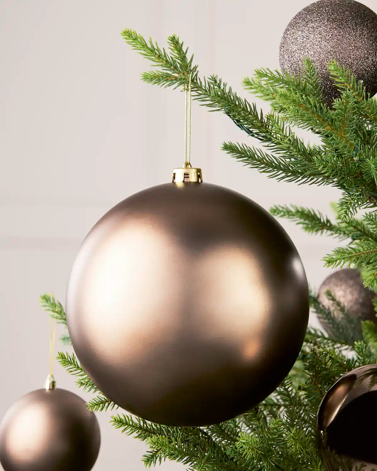 Mocha 20 cm oversized Matt shatterproof bauble displayed on a Christmas tree with coordinating Mocha baubles.
