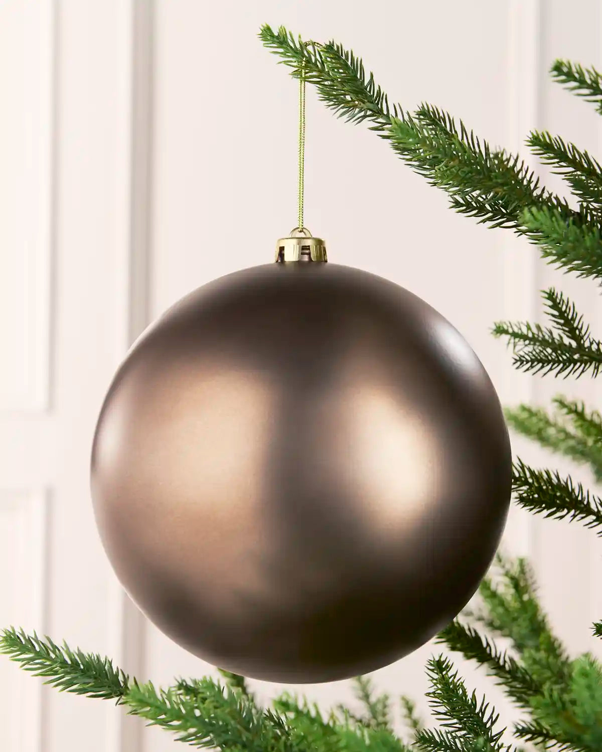 Mocha 20 cm oversized Matt shatterproof bauble hanging on a Christmas tree with a gold cap and matching string.
