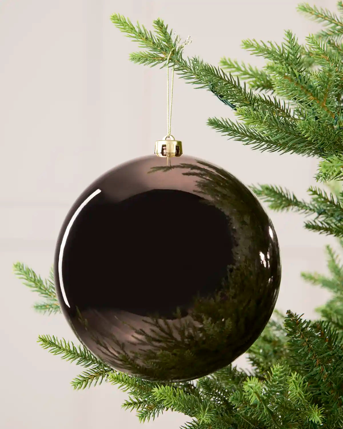 Mocha 20 cm oversized Shiny shatterproof bauble hanging on a Christmas tree with a gold cap and matching string.
