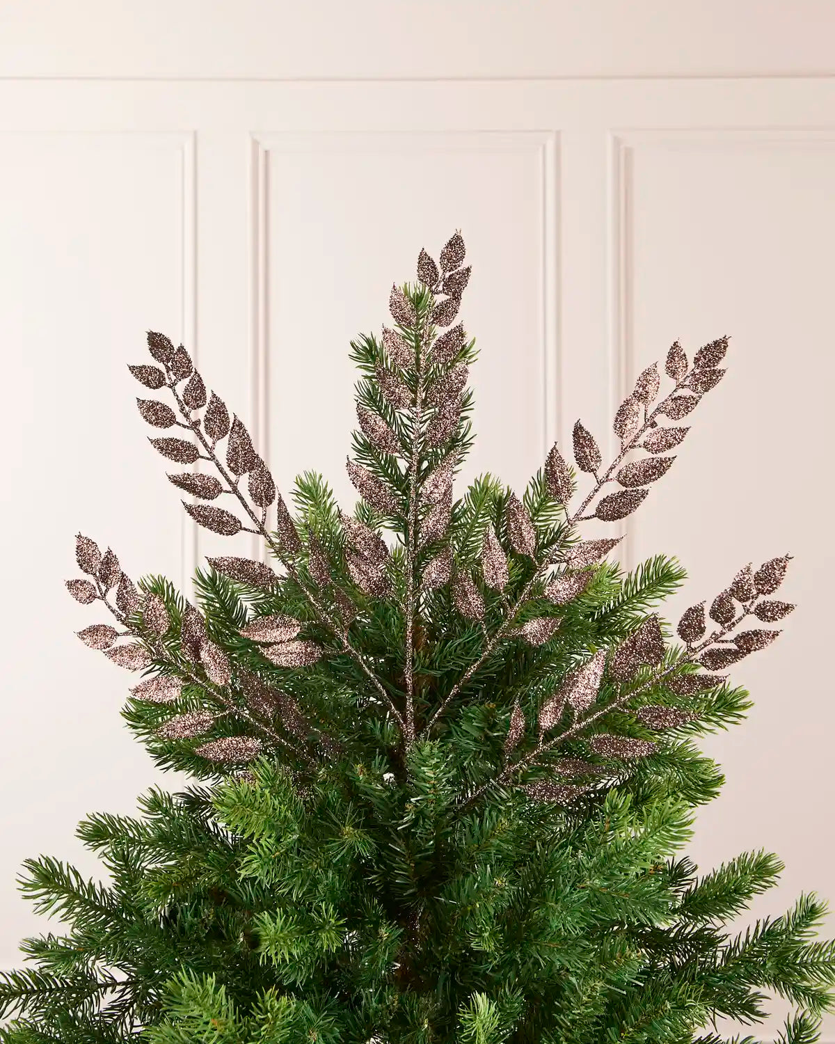 Mocha Leaf Christmas Tree Spray placed in Christmas as a tree topper fanned out with a plain cream background. 