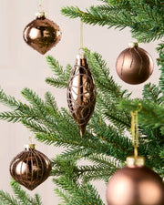 Mocha coloured Glass baubles hanging with gold string on a Christmas tree against a cream background