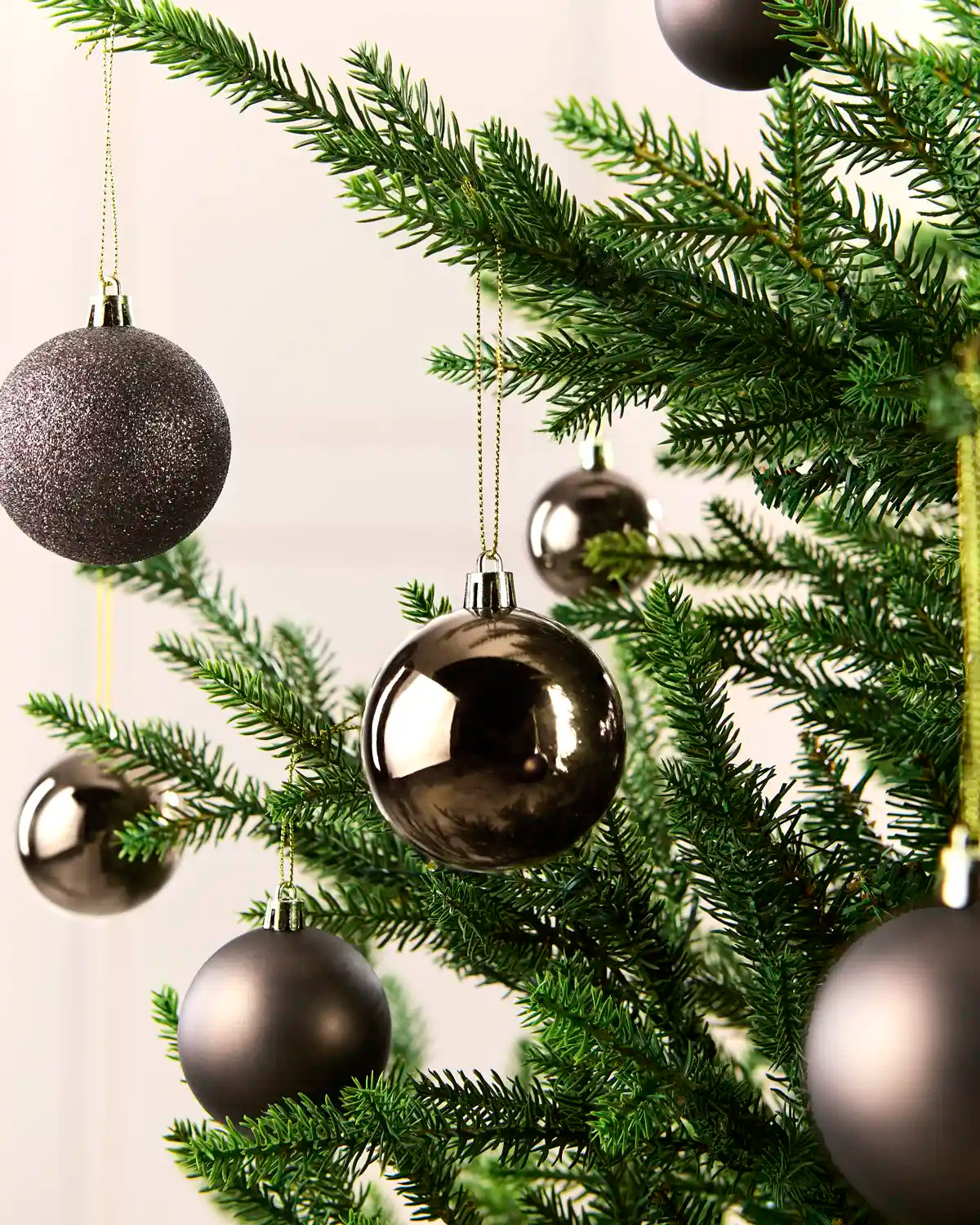 Mocha coloured baubles hanging on a Christmas tree against a cream wall