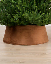 Mocha coloured velvet tree skirt under a Christmas tree on a Light brown floor
