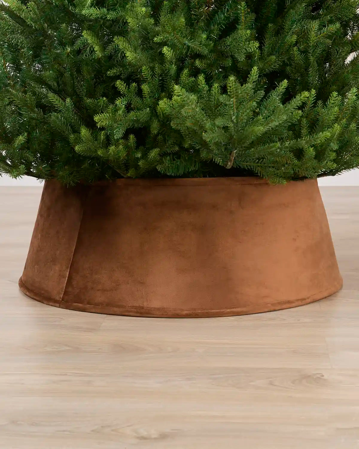 Mocha coloured velvet tree skirt under a Christmas tree on a Light brown floor