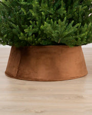 Mocha coloured velvet tree skirt under a Christmas tree on a Light brown floor