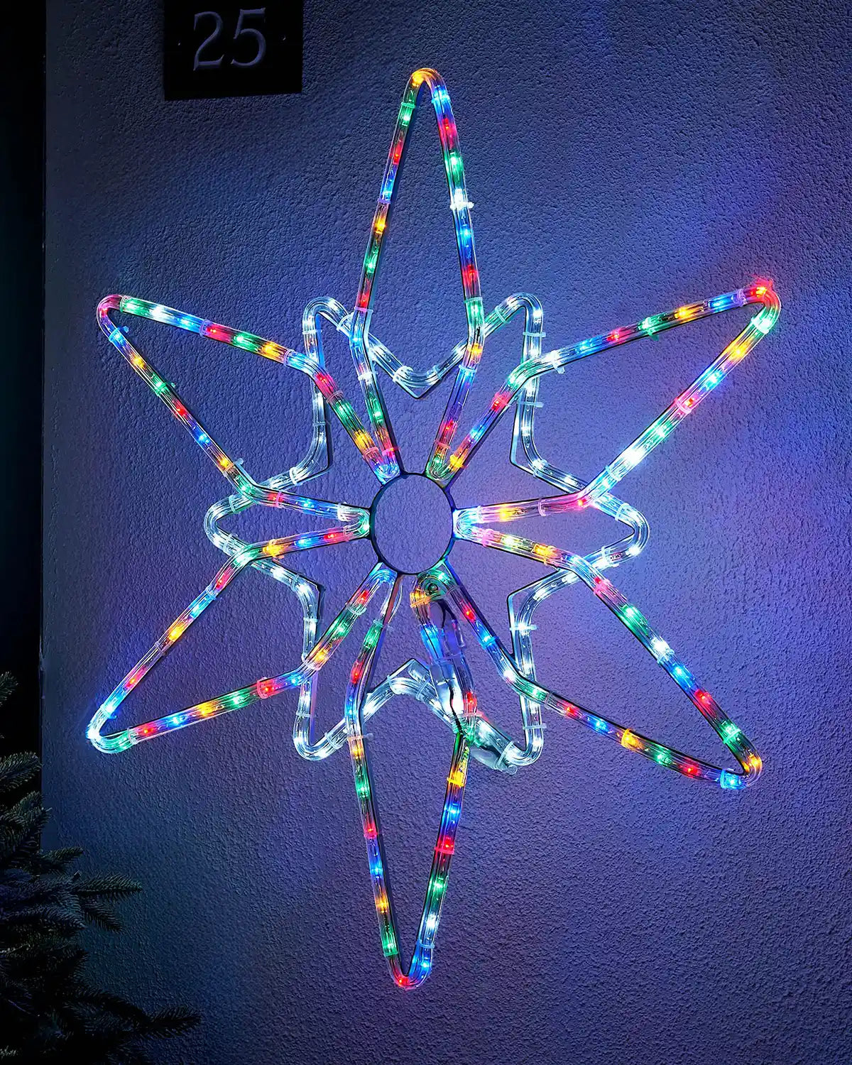 Multi colour LED Northern star on a blue garden wall