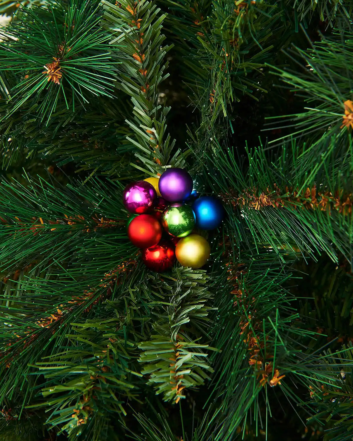 Multi coloured berry cluster baubles on a Christmas tree close up