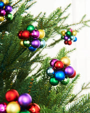 Multi coloured berry cluster baubles on a Christmas tree with a white background