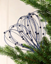 Navy Glitter Nest Christmas Tree Pick placed in green Christmas tree branches with a cream background
