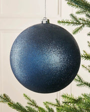 Navy blue glitter oversized bauble on a Christmas tree branch