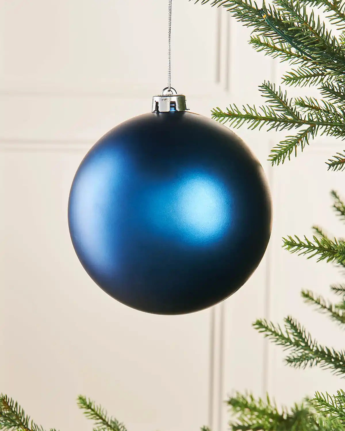 Navy blue matt oversized 15cm bauble on a Christmas tree branch