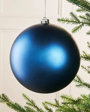 Navy blue oversized bauble on a Christmas tree branch
