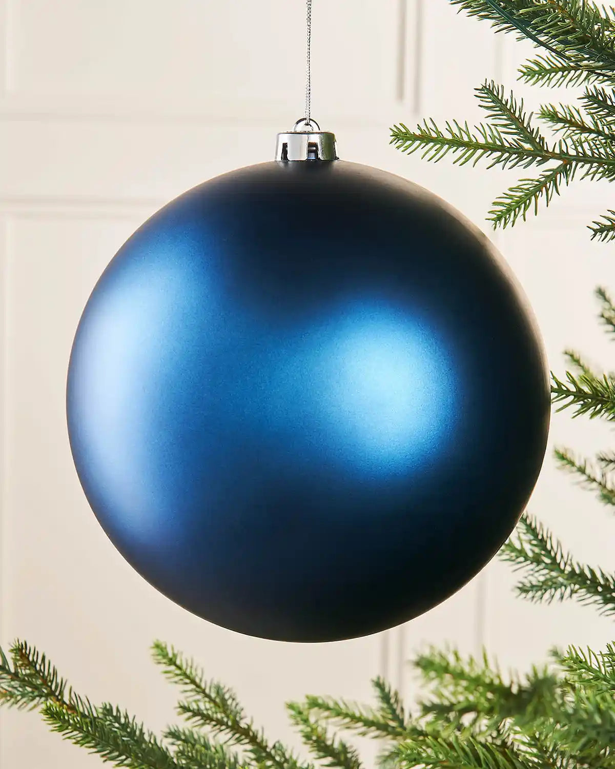 Navy blue oversized bauble on a Christmas tree branch