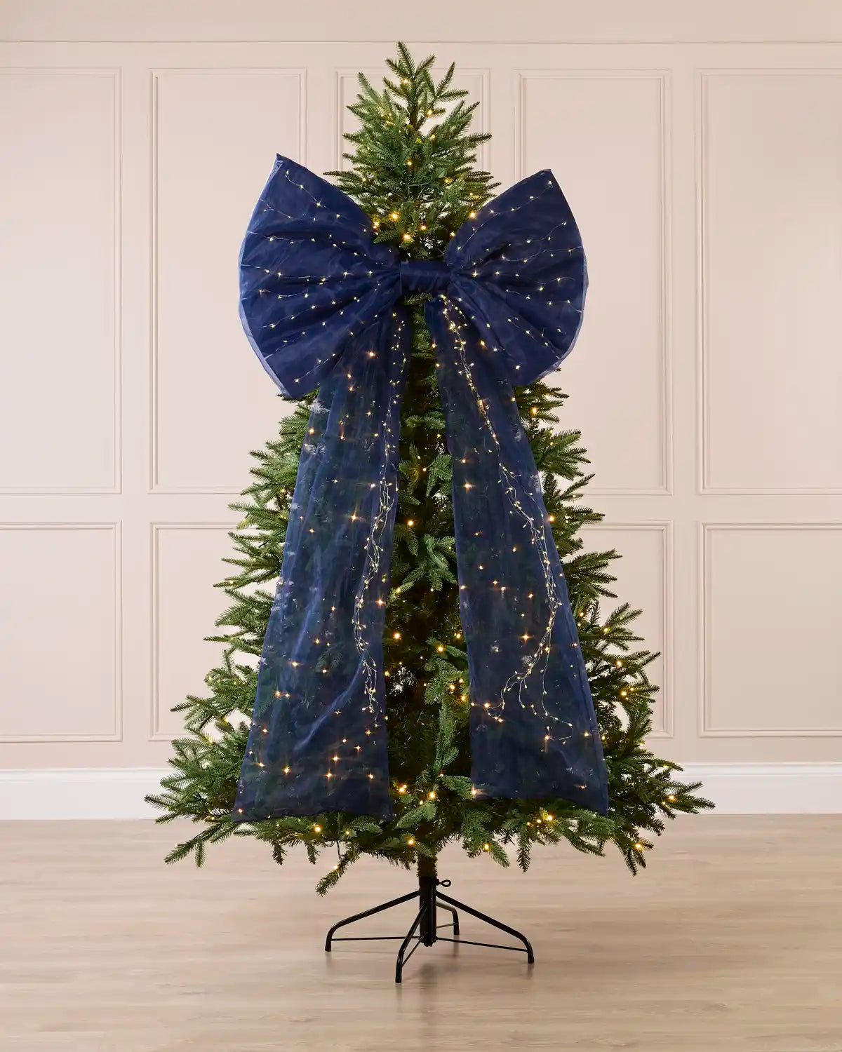 Navy blue pre-lit Christmas bow displayed on a decorated Christmas tree.