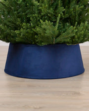 Navy coloured velvet tree skirt under a Christmas tree on a Light brown floor
