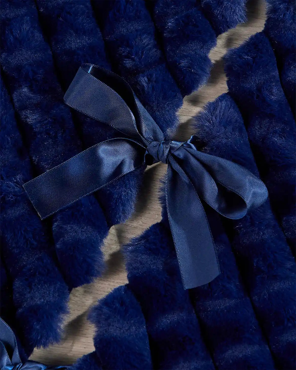 Navy faux fur diamond tree skirt ribbon ties on light wooden flooring