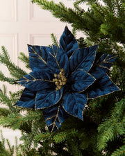 Navy glitter artificial poinsettia flower displayed on a Christmas tree, featuring layered pointed petals with gold glitter outlining the edges and veins and a sparkling gold center.
