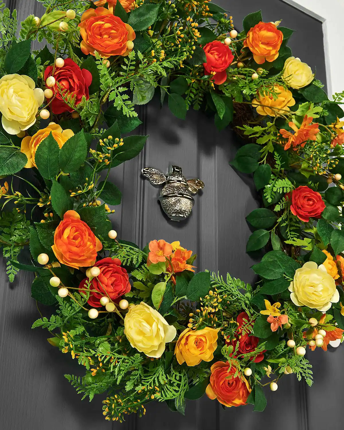 Orange, 28 Inch, Artificial Floral Rose Spring Wreath on a Black door, low angle shot.